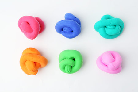 Different colorful play dough on white background, flat lay