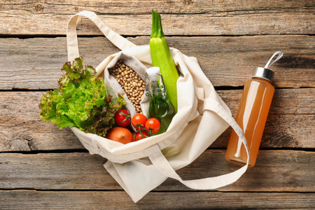 Shopper bag with products on wooden background, top view. Eco friendly lifestyle