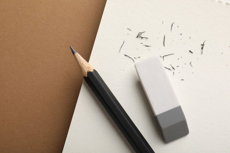 Eraser, pencil, scraps and notebook on brown background, top view. Space for textの写真素材