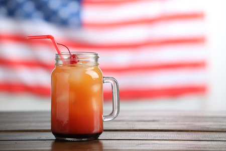 Tasty cocktail in mason jar on wooden table against flag of USA, space for textの写真素材