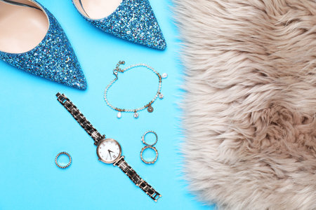 Beautiful shoes, faux fur and stylish accessories on light blue background, flat lay