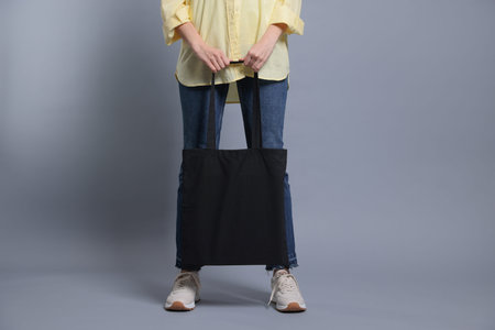 Woman with blank shopper bag on grey background, closeup. Mockup for designの写真素材
