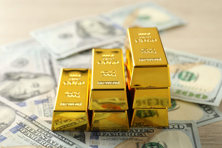Shiny gold bars and dollar banknotes on table, closeup