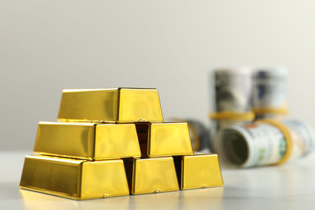 Shiny gold bars on light table against gray background, closeup. Space for textの写真素材
