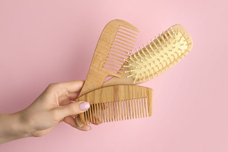 Woman with wooden brush and combs on pink background, closeup