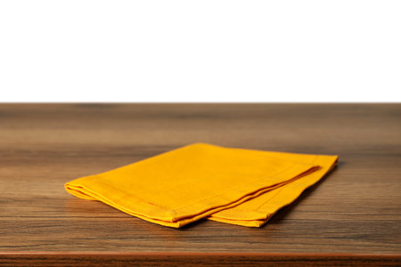 Orange napkin on wooden table against white backgroundの写真素材