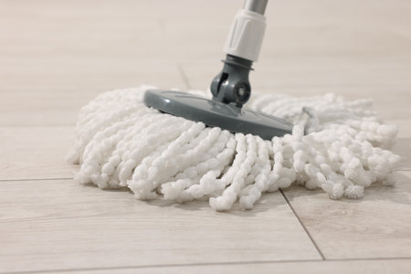 String mop on wooden floor, closeup. Cleaning equipmentの写真素材