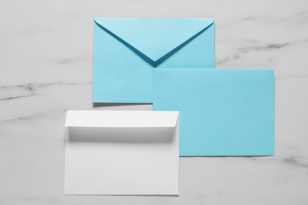 Paper envelopes on white marble background, flat lay. Mockup for design
