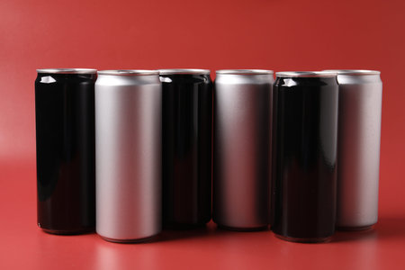 Many aluminum cans of beverage on red background