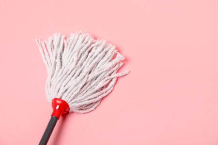 String mop on pink background, above view. Space for text