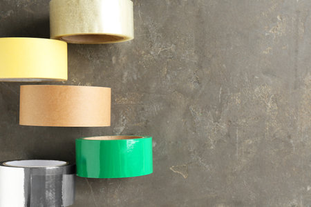 Rolls of different adhesive tapes on gray table, flat lay. Space for textの写真素材