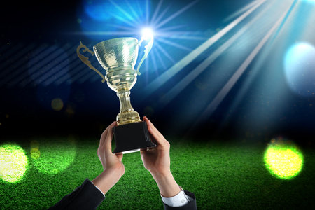 Man holding golden trophy under lights at stadium, closeupの写真素材