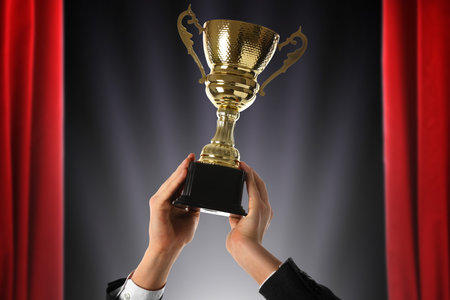 Man holding golden trophy at stage, closeupの写真素材