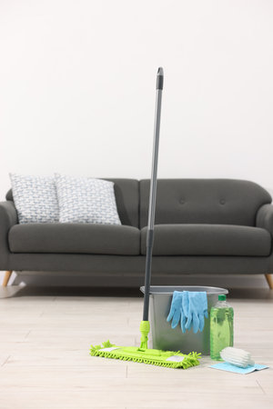 Microfiber mop and bucket with cleaning supplies on wooden floor indoorsの写真素材