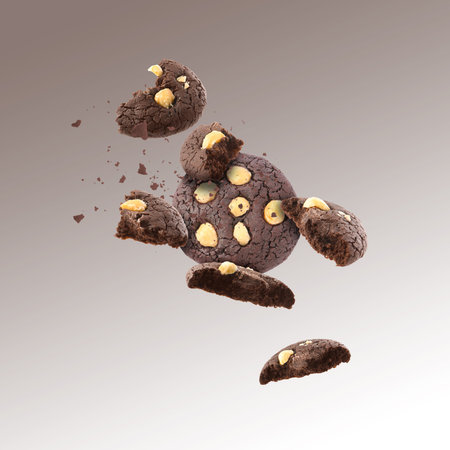 Yummy chocolate cookies with hazelnuts in air on brown gradient backgroundの写真素材
