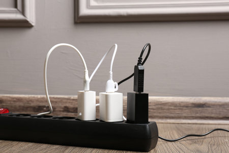 USB adapters with charge cables in power strip on floor indoors, closeup
