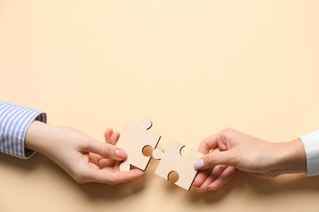 Business strategy and teamwork concept. Partners putting puzzle pieces together on beige background, top view. Space for textの写真素材
