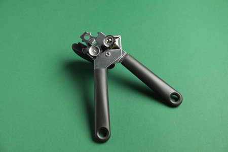 One can opener on green background. Kitchen utensil