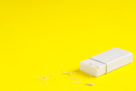 One eraser and scraps on yellow background, closeup. Space for textの写真素材