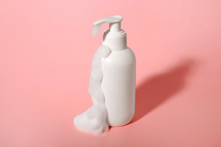 Bottle of cosmetic product with foam on pink backgroundの写真素材
