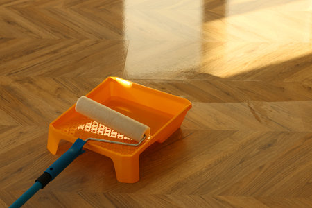 Process of polishing. Roller and tray with varnish on floor, space for text