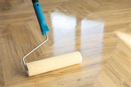 Polishing parquet with roller and varnish indoors, closeup. Space for textの写真素材