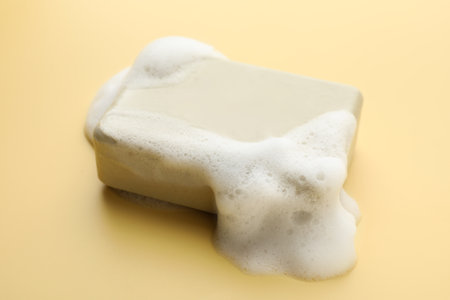 Soap bar with foam on yellow background, closeupの写真素材