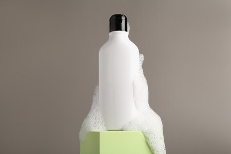 Bottle of cosmetic product with foam on podium against grey backgroundの写真素材