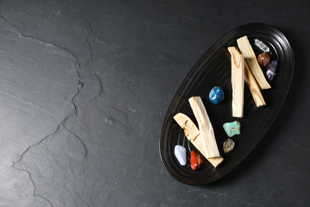 Palo santo sticks and gemstones on black table, top view. Space for textの写真素材