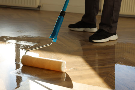 Man polishing parquet with varnish indoors, closeupの写真素材