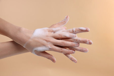 Woman washing hands with foaming soap on beige background, closeup. Hygieneの写真素材
