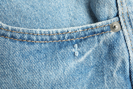Stylish light blue jeans with pocket as background, top view