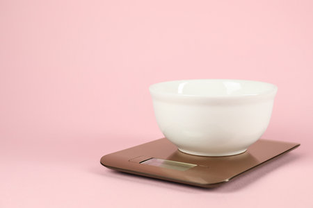 Electronic kitchen scale with bowl on pink background. Space for textの写真素材