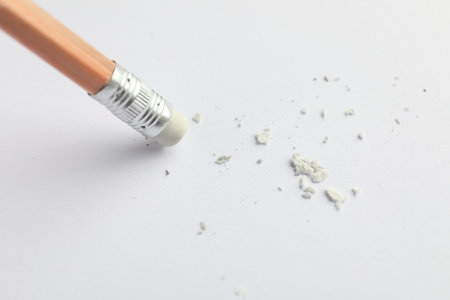 Using pencil with eraser on white sheet of paper, closeup