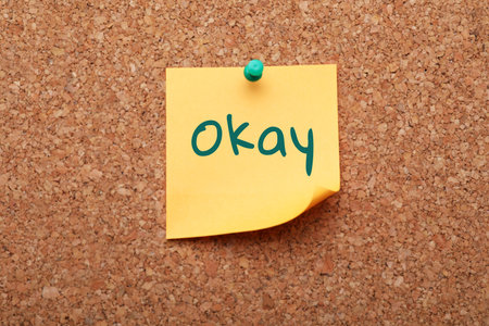 Paper note with word Okay pinned to cork backgroundの写真素材