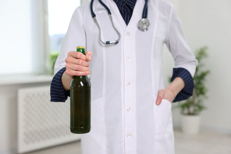Healthcare specialist with bottle of beer in clinic, closeup. Addiction treatmentの写真素材