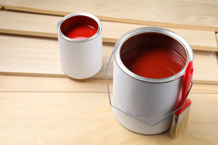 Cans of red paint, brush and planks on wooden tableの写真素材