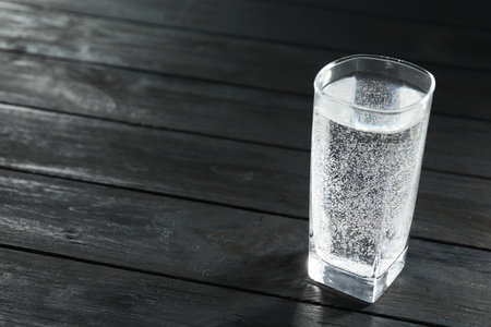 Refreshing soda water in glass on black wooden table, closeup. Space for textの写真素材