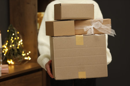 Woman with parcels and gift box indoors, closeup. Space for text