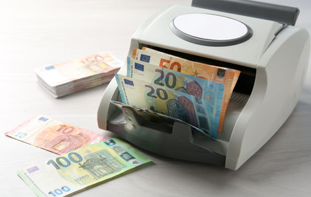 Money counter machine with euro banknotes on white wooden table, closeupの写真素材