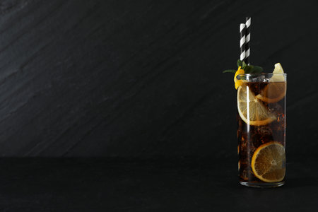 Fresh iced cola with lemon slices and mint on black table. Space for text