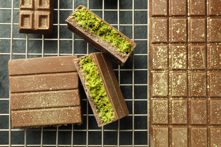 Delicious chocolate bars with pistachios and knafeh on black table, top viewの写真素材