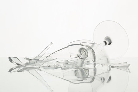 Pieces of broken wine glass on table against white background, closeupの写真素材