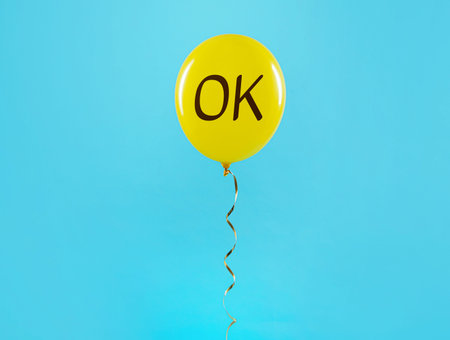 Yellow balloon with abbreviation OK on light blue background