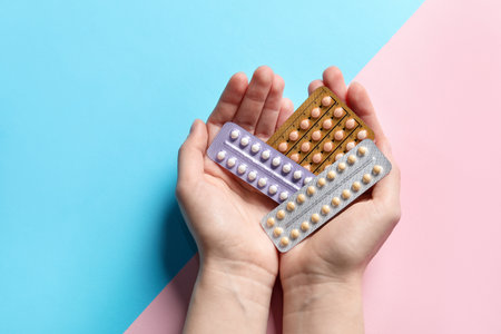 Woman holding blisters of contraceptive pills on color background, closeupの写真素材