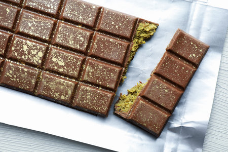 Delicious chocolate with pistachios and knafeh on white wooden table, top view