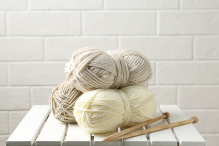 Skeins of yarn and knitting needles on white wooden table