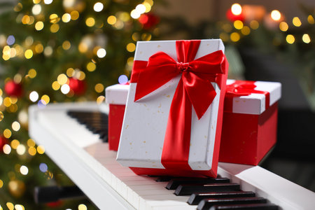 Gifts on electric piano against Christmas tree with blurred lights, closeup. Bokeh effectの写真素材
