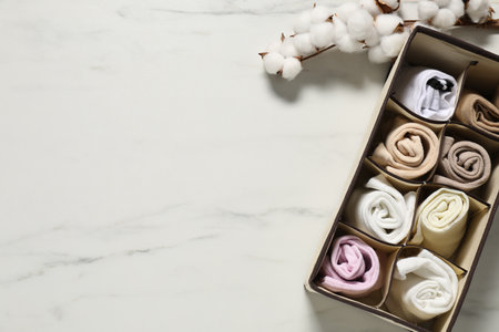 Organizer with different socks and cotton branch on white marble table, flat lay. Space for textの写真素材