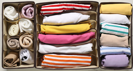 Organizers with folded clothes on table, flat layの写真素材